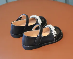 Detaillierte Nahaufnahme von schwarzen Mädchen-Mary-Janes mit eleganten Perlenverzierungen
