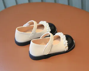 Detailansicht von cremefarbenen und schwarzen Mary Janes für Mädchen mit Perlen.