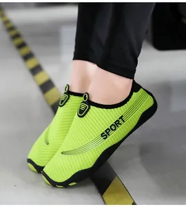 Close-up view of breathable lime green aqua shoes worn on a grey floor with caution stripes