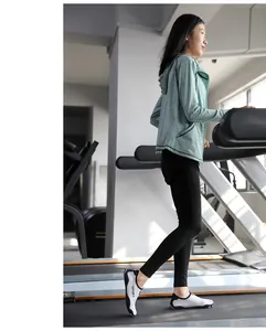 Woman wearing white and black breathable fitness shoes while walking on a gym treadmill
