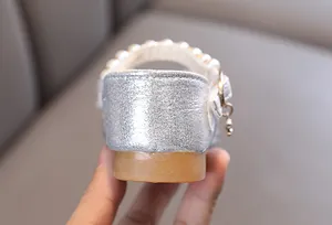 Primer plano del talón y la tira de perlas de los zapatos de princesa plateados niña