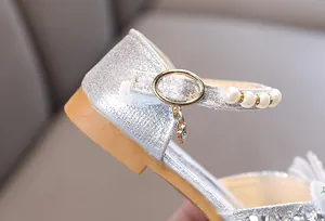 Primer plano de zapato de princesa plateado con purpurina, perlas y hebilla de oro