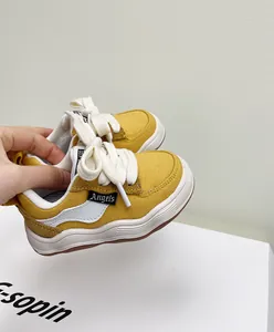 Detailopname van gele canvas peutersneakers met zachte witte zolen en katoenen veters