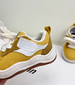 Detailopname van gele baby loopschoenen met hoogwaardige canvas en suède materialen.