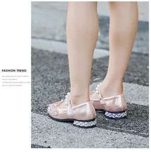 Close-up detail of pink sparkling girl's princess shoes featuring pearls and rhinestones