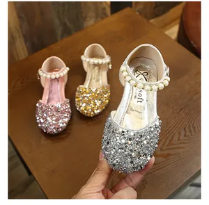 Détail d'une chaussure de princesse argentée pailletée avec bride en perles pour fille
