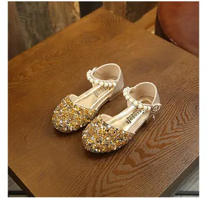 Détail des chaussures de princesse à paillettes dorées avec bracelet de perles élégant
