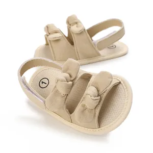 Detailed close-up view of beige cotton baby sandals with soft soles and decorative bows