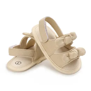 Close-up of beige baby sandals with soft cotton fabric and cute double bow decoration.