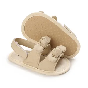 Close-up detail of beige cotton baby sandals featuring a soft anti-slip sole and cute bow