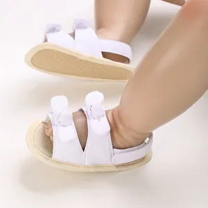 Close-up of white baby cotton sandals with bow details and soft anti-slip soles