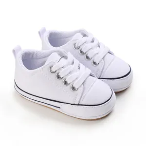 Detailed macro view of white canvas baby walking shoes featuring soft soles and secure laces