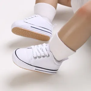 Detailed view of white baby canvas sneakers with non-slip soft soles on baby doll's feet