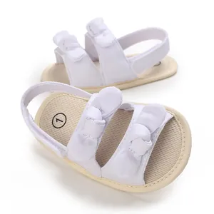Close-up of white cotton soft-soled baby sandals featuring charming double bow accents.