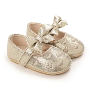 Close-up detail of gold infant princess walking shoes with bow and heart embroidery