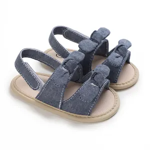 Detail of blue denim baby sandals with soft soles and cute knot bow decorations.
