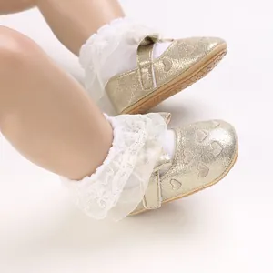 Close-up detail of golden glittery baby girl princess walking shoes with white lace socks