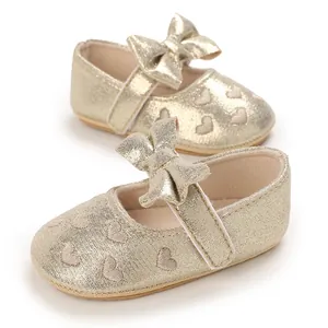 Detail view of gold baby girl princess walking shoes with bow and heart embroidery.