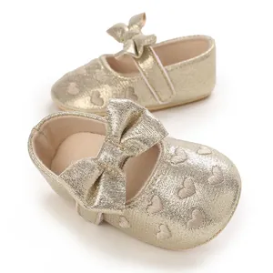 Detailed close-up of gold glitter baby princess shoes with bow and heart pattern design