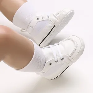 Close-up view of white soft-soled baby pre-walker shoes with laces and anti-slip dots