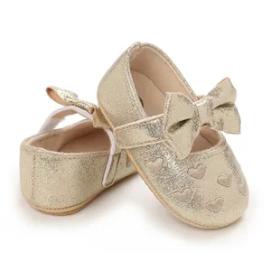 Detail view of gold glitter baby girl walking shoes with bow and heart pattern