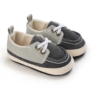 Nahaufnahme von weichen Segeltuch-Babyschuhen mit grauem Patchwork und weißen Schnürsenkeln