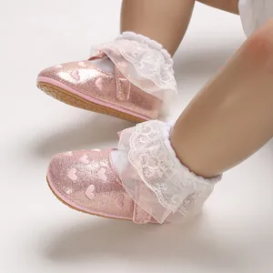 Detailed close-up of pink glitter baby walking shoes featuring heart patterns and lace ruffles