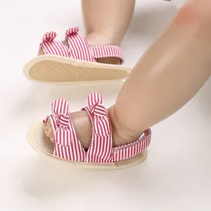 Gedetailleerde weergave van rood-wit gestreepte baby sandalen met strik en zachte zooltjes