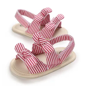 Detailweergave van babysandalen met rood-wit gestreept patroon en strikjes.