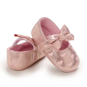 Detailed view of pink glitter baby princess shoes with bow and heart patterns