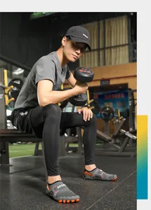 Scarpe da ginnastica grigie ad asciugatura rapida con suole arancioni in palestra