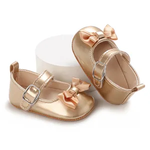Detailed view of the elegant gold bow and metallic buckle on baby girl's walker shoes.