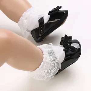 Macro view of black patent leather baby princess shoes featuring a delicate bow detail