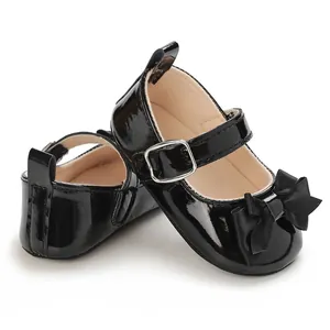 Close-up of black patent leather baby Mary Jane shoes with bow detail and soft sole.