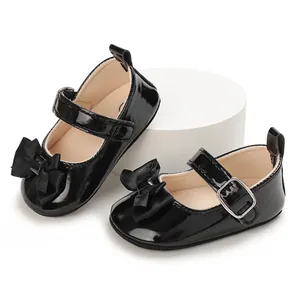Detailed view of glossy black patent baby walking shoes with ribbon bow and buckle strap