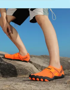 Scarpe da acqua arancioni per uomo e donna su un terreno di spiaggia roccioso