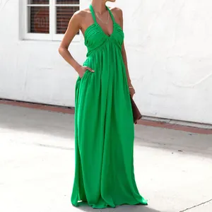 Dettaglio dell'abito lungo verde allacciato al collo con scollo a V profondo e tasche.