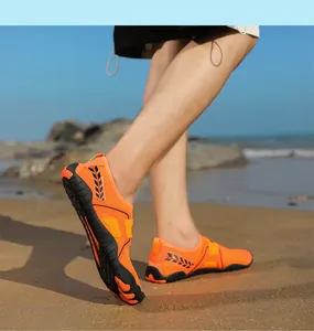 Primo piano di scarpe da scoglio arancioni traspiranti indossate su una spiaggia assolata