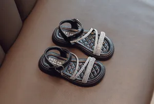 Close-up view of girls' black Roman sandals featuring sparkly rhinestone cross straps