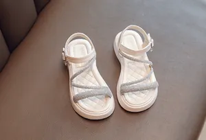 Close-up of girls' white Roman sandals featuring sparkly rhinestone straps and soft soles.