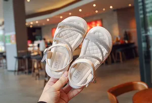 Detailed view of girls' white sandals with sparkling rhinestone straps and soft sole
