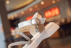 Detail view of girls' white Roman sandal with elegant silver buckle and rhinestone straps