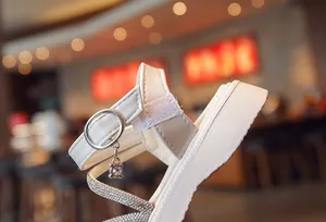 Detail of girls' white Roman sandals with rhinestones and soft thick sole