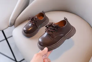 Gedetailleerd overzicht van bruine Britse stijl leren kinderschoenen op een beige stoel
