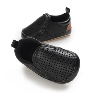 Close-up of black PU leather baby shoes with breathable perforated design and soft soles.