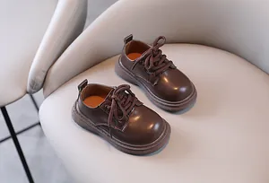 Bruine leren schoenen in Britse stijl voor jongens op een beige fauteuil zitting