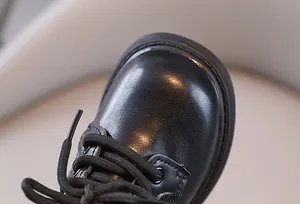 Macro detail van hoogwaardige zwarte Britse stijl kinderschoen met leertextuur