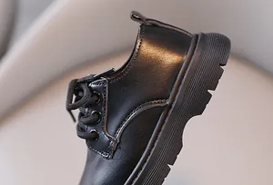 Detailopname van zwarte leren schoenen voor jongens in Britse stijl met veters en zool.