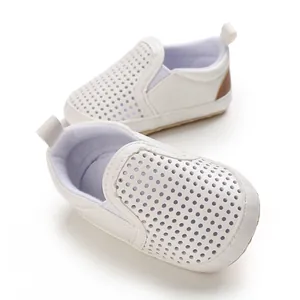 Close-up of white perforated PU leather baby pre-walking shoes with soft soles