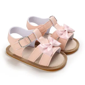 Detailed view of pink baby girl sandals with patent leather bow and buckle strap
